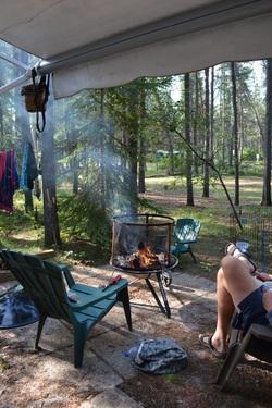 person relaxing by a smouldering fire at their campsite