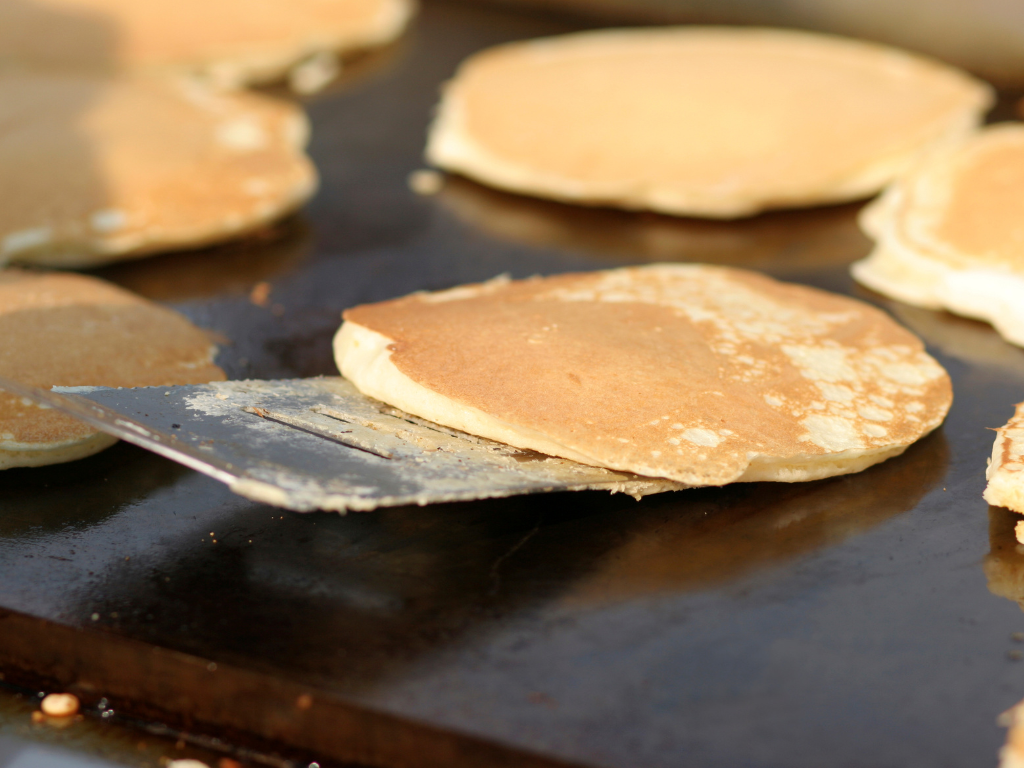 pancakes being flipped on an outdoor cooktop